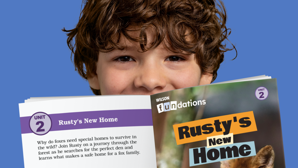 a student holding up a fluency reader with the title Rusty's new home on the cover